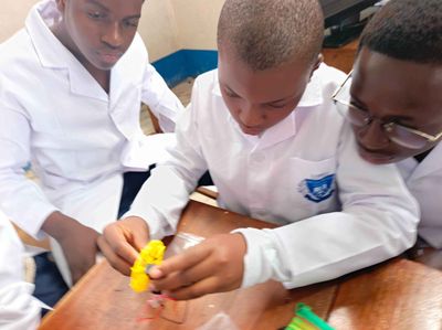 Students in lab coats assembling a small motor and circuit