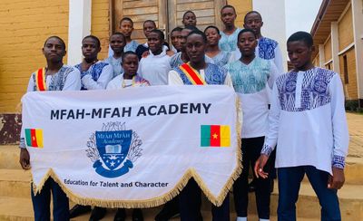 Students holding the Mfàh’Mfàh Academy banner reading Education for Talent and Character, flanked by Cameroon flags