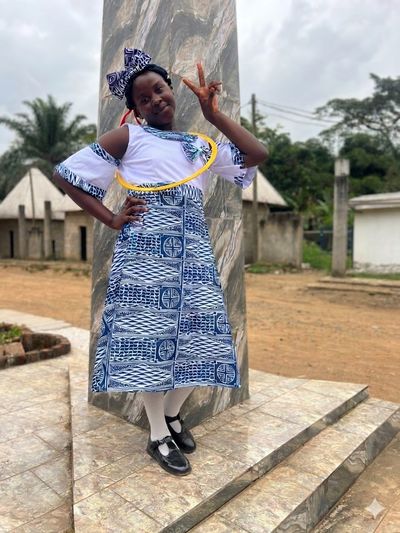A student in full indigo Ndop ceremonial dress with a matching headwrap